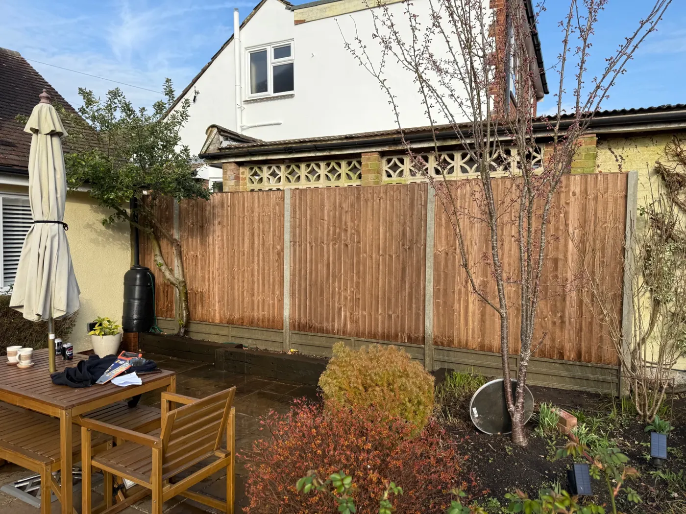 Brown feather edge fence panels behind a patio in a Farnham garden