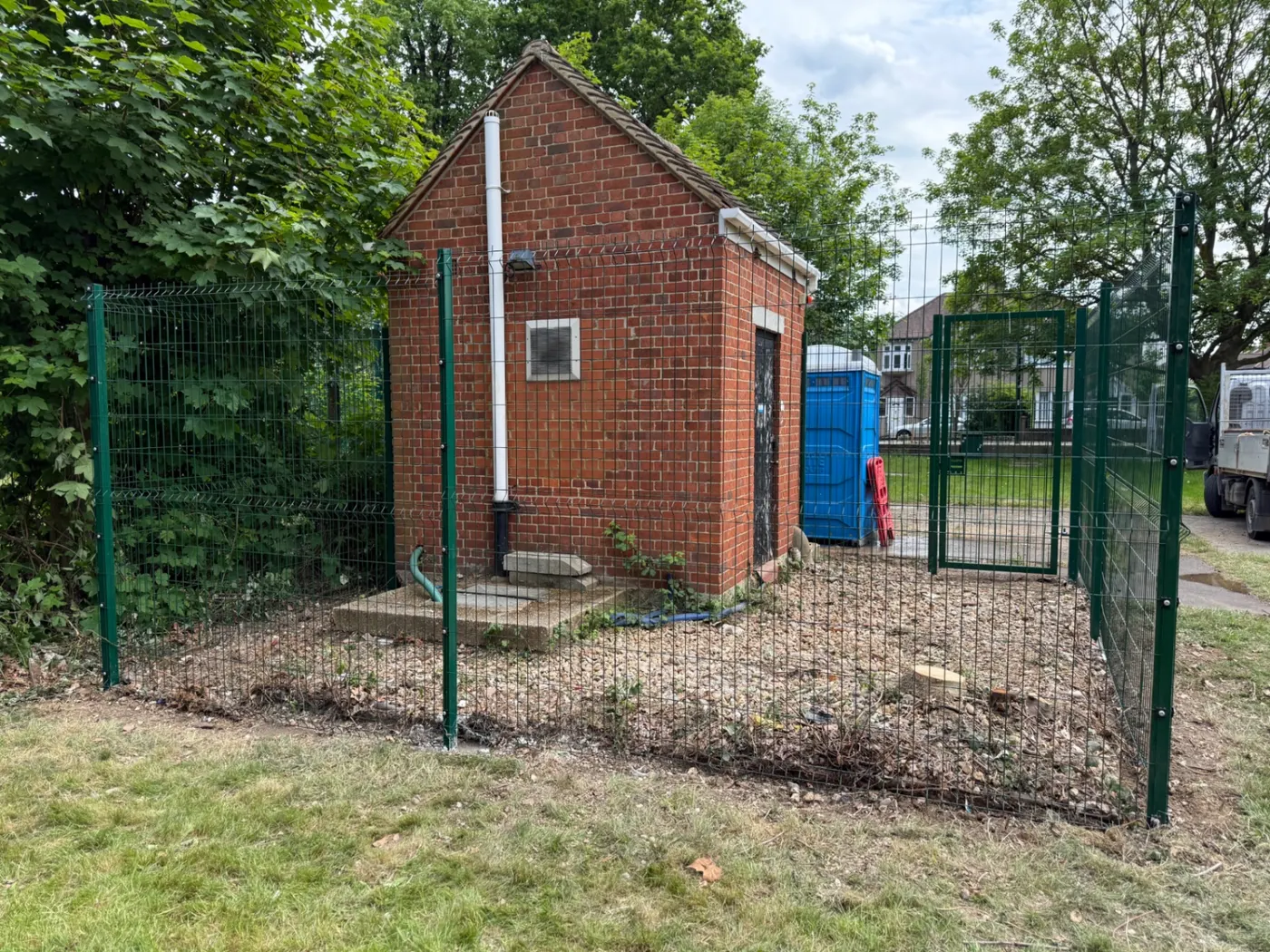 Green mesh security fencing and gate around a utility building near Farnham