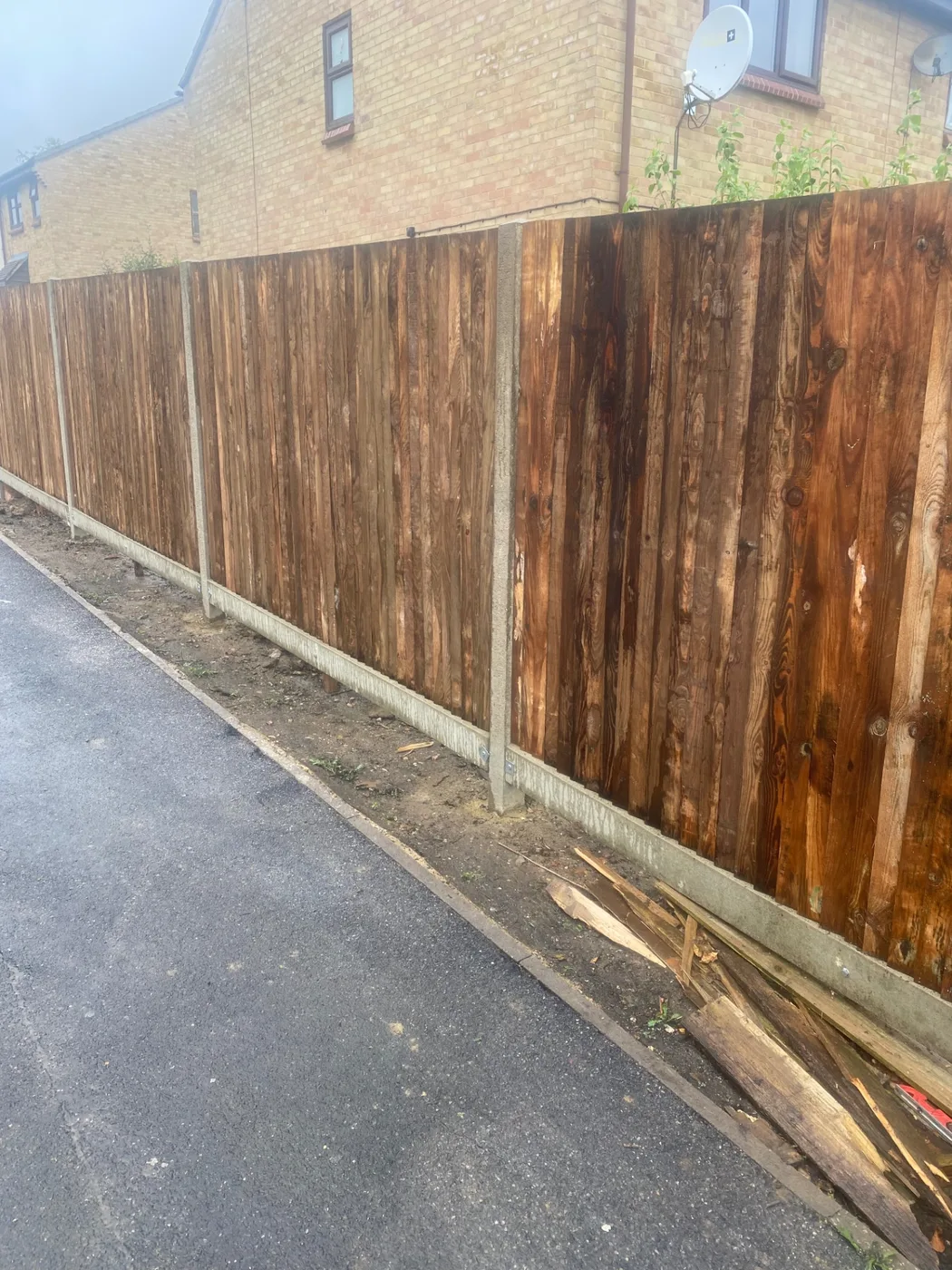 Dark stained closeboard fencing installed along a residential road