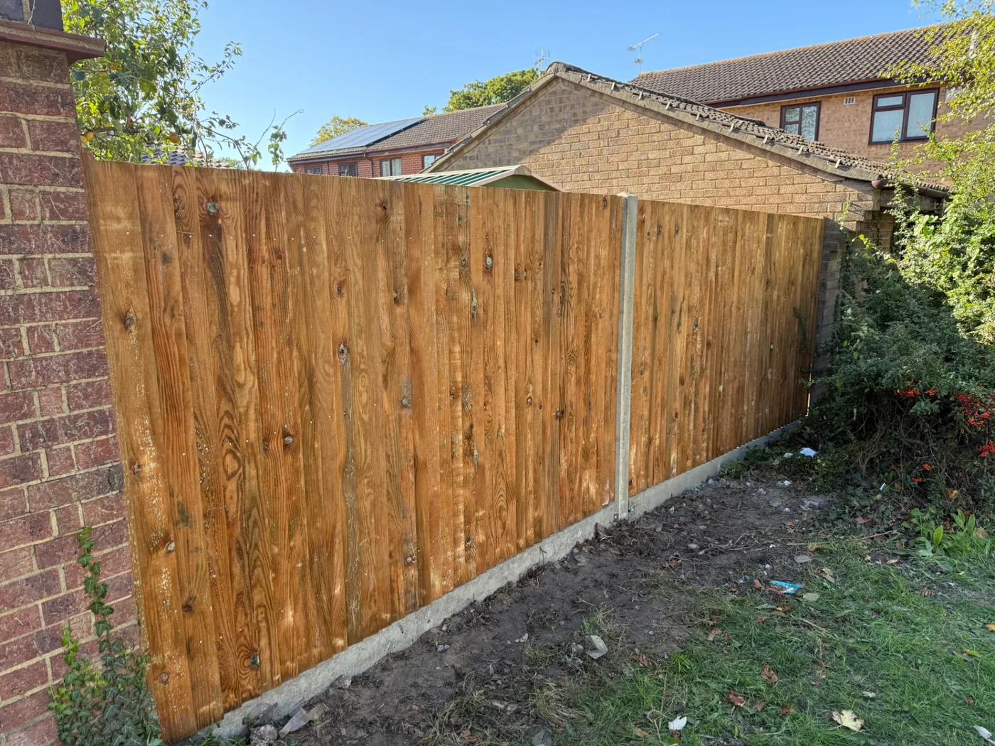 Closeboard boundary fence built beside a brick wall in Surrey