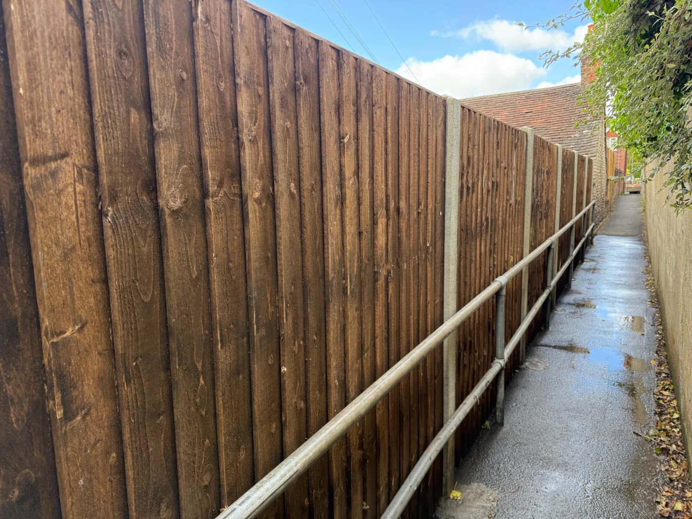 Tall dark stained closeboard fence along an alleyway in Farnham