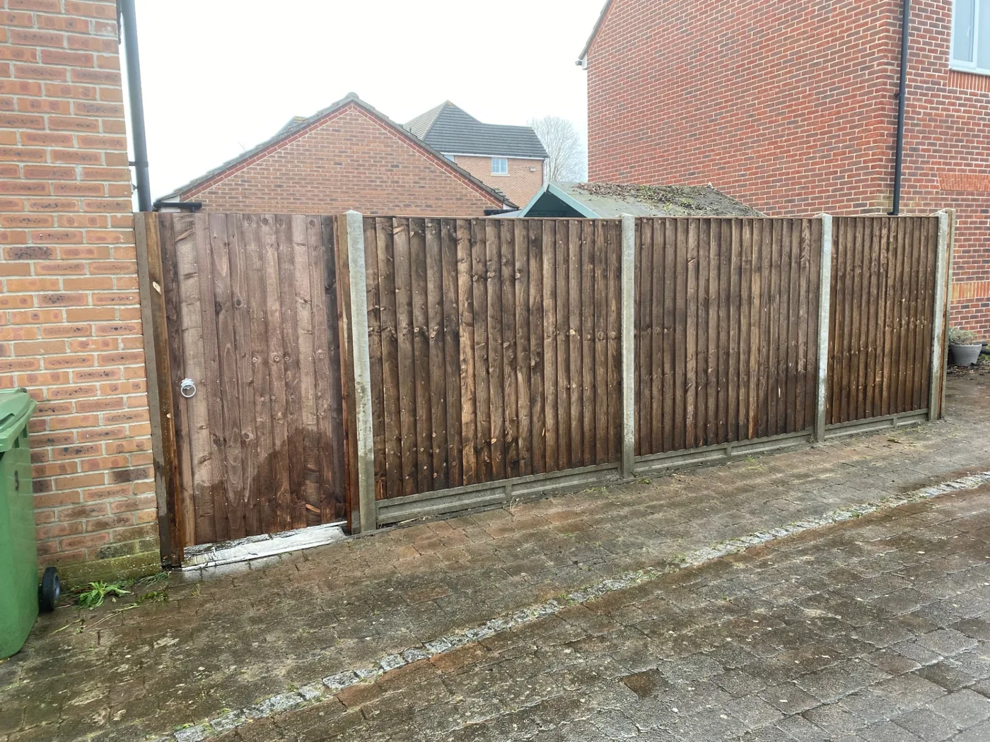 Brown closeboard fence panels and matching side gate on a driveway