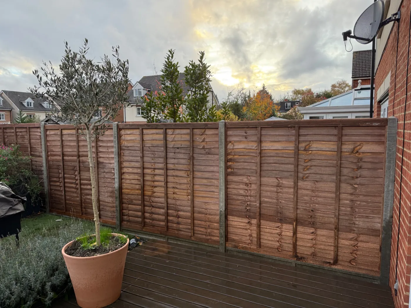 Lap fence panels installed with concrete posts beside a decked garden