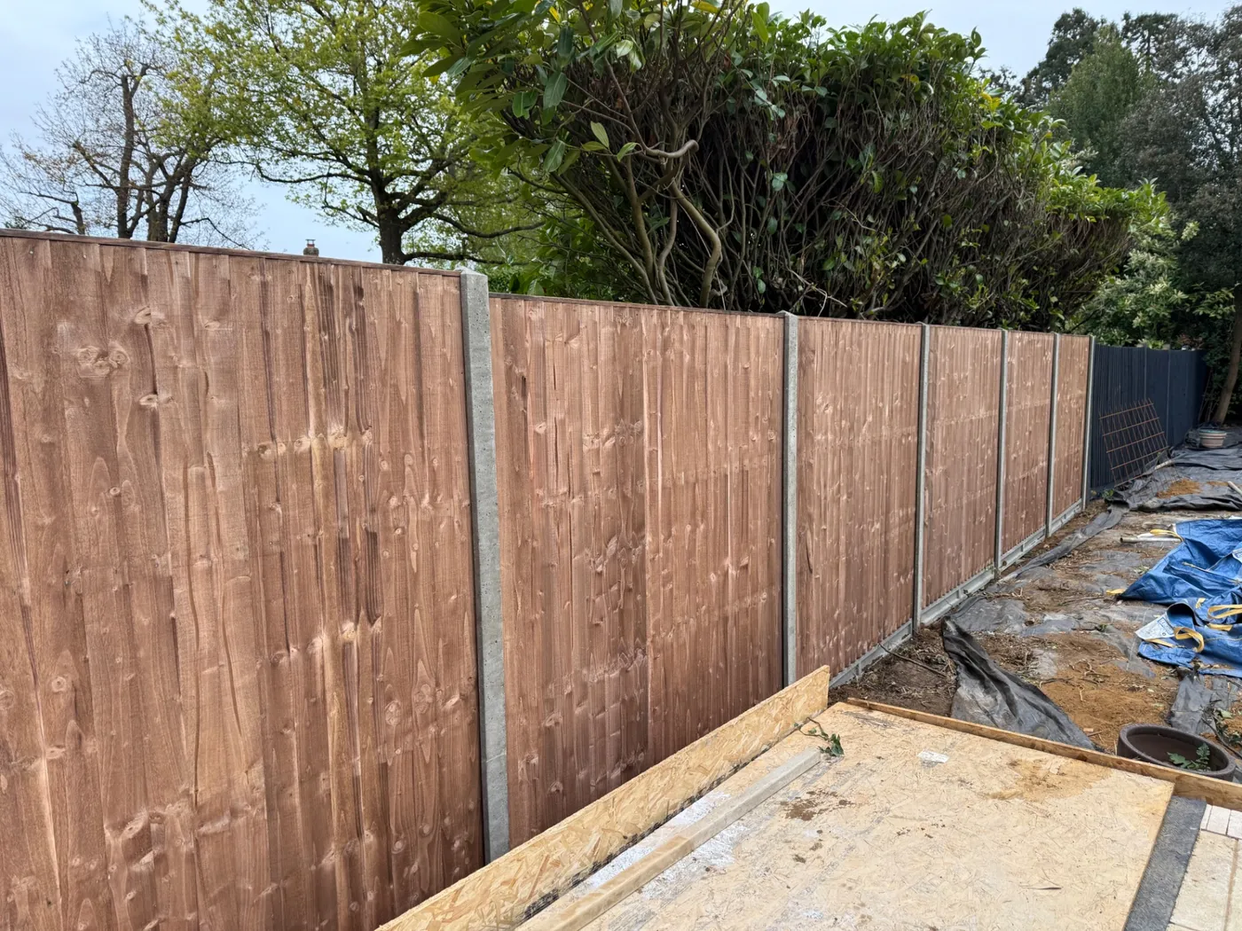 Brown feather edge fence panels installed with concrete posts and gravel boards