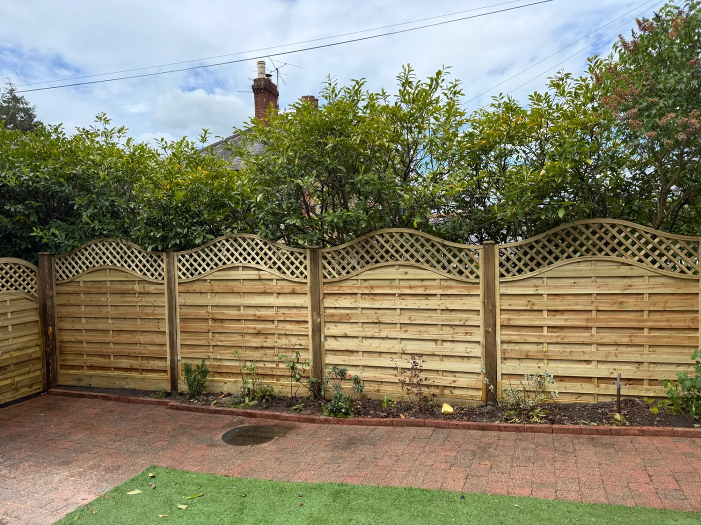 Decorative wave trellis top fence panels installed in a Farnham garden