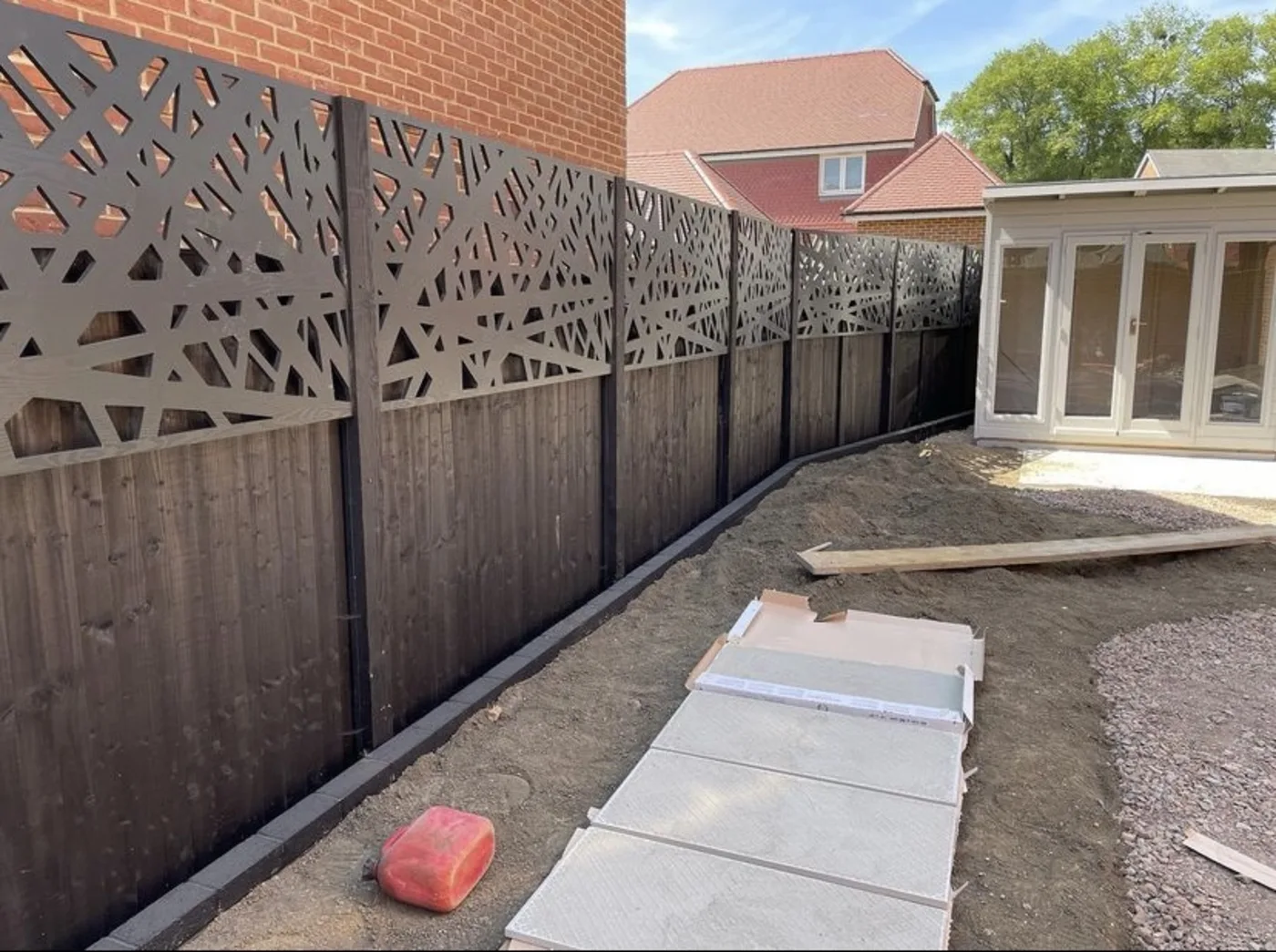 Decorative laser cut fence toppers fitted above dark garden fence panels