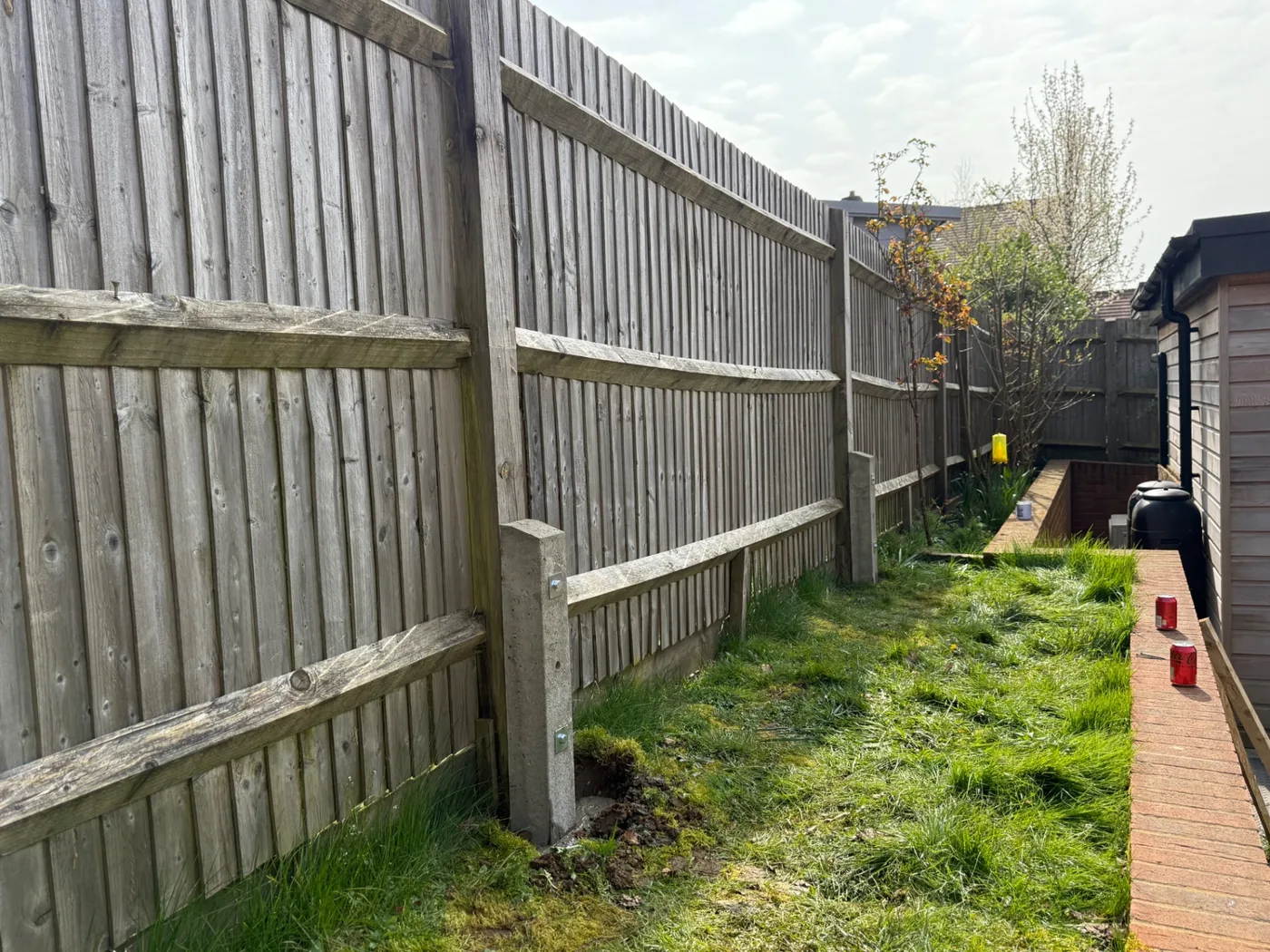 Leaning weathered fence panels with concrete posts awaiting repair in Farnham